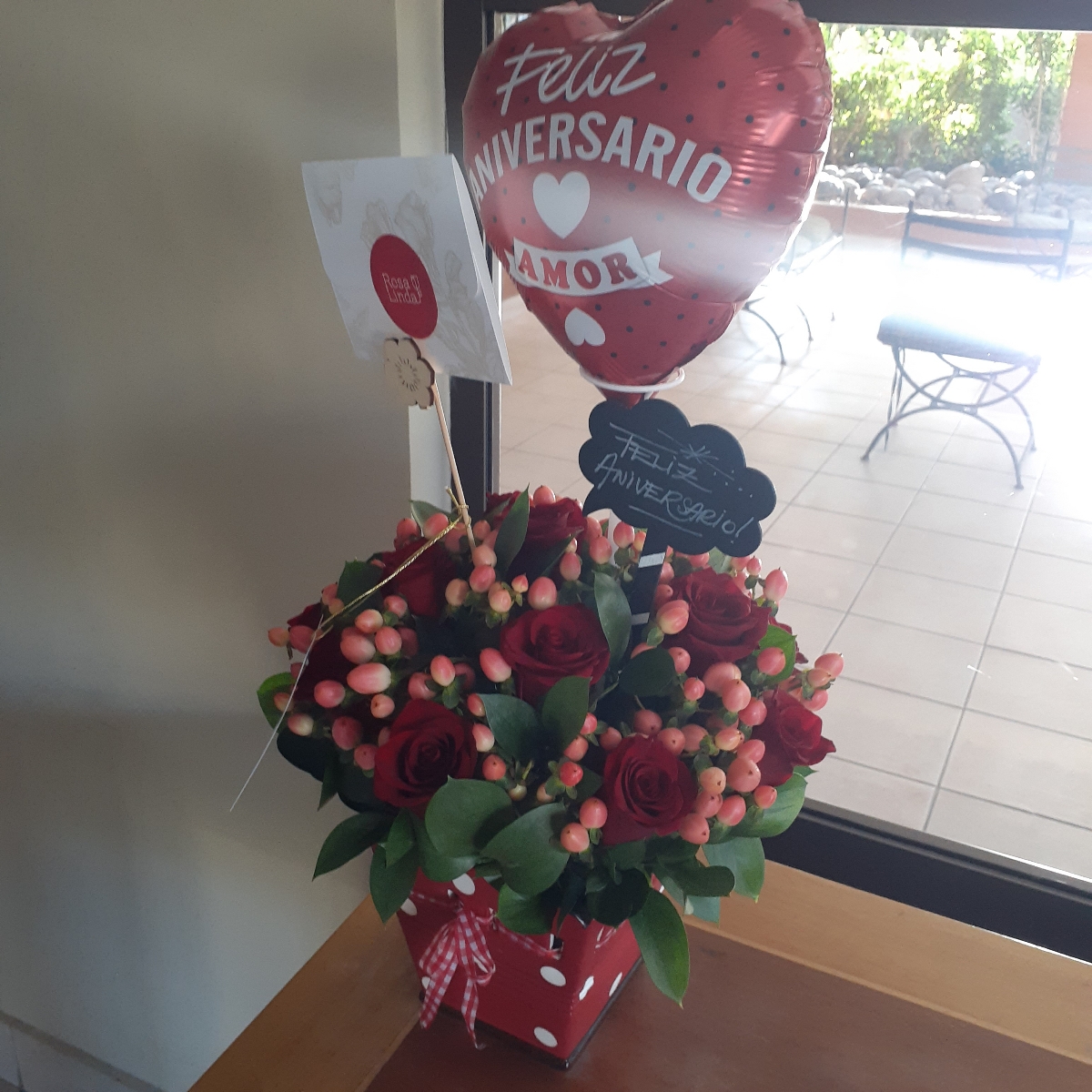 Sorpresa de Aniversario - Arreglo floral de aniversario con rosas rojas e hypericum; globo y pizarra de aniversario - Pedido 252600